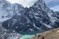 Türkisfarbener Bergsee inmitten schneebedeckter Berglandschaft.