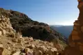 Blick durch eine Steinmauer auf ein Bergdorf in einer felsigen Berglandschaft.