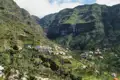 Blick auf ein Dorf in einem Tal mit Terrassenfeldern und umliegenden Bergen.