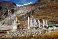 Gebetsfahnen und ein Stupa vor einer Berglandschaft.