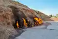 Flammen aus Steinen an einem Berghang.