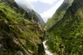 Ein Bergpfad in einem üppigen Tal mit einem Flusslauf.