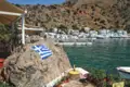 Griechische Flagge auf einem Felsen, mit Blick auf den Hafen und die weißen Häuser im Hintergrund.