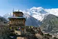 Traditioneller Steinbogen mit Gebetsfahnen und Blick auf die schneebedeckten Berge des Himalaya.