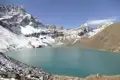 Türkisfarbener Bergsee umgeben von schneebedeckten Gipfeln.