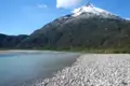 Szene mit einem Fluss und einem schneebedeckten Berg im Hintergrund.