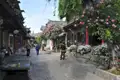 Gepflasterte Straße mit traditionellen Gebäuden und blühenden Pflanzen.