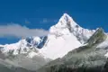 Panorama einer schneebedeckten Bergkette unter blauem Himmel.