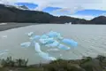 Eisberge treiben im See vor einer Bergkulisse.