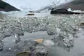 Eisschollen und Steine im Vordergrund, Gletscher und Berge im Hintergrund.