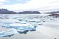 Eisschollen treiben im Wasser vor der Küste, was die Auswirkungen der Reise auf die polare Umgebung zeigt.