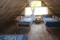 Zwei Einzelbetten in einem Zimmer mit Dachschrägen aus Bambus und Moskitonetz.