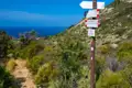 Wegweiser auf einem Wanderweg mit Richtungsangaben nach Pomonte, Colle della Grottaccia und Valle dei Mori.