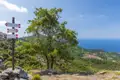 Wegweiser mit Richtungsangaben nach Marciana, Poggio und Monte Capanne auf Elba. Im Hintergrund das Meer und eine Ortschaft.