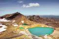 Türkisfarbene Bergseen in einer vulkanischen Landschaft mit Schneefeldern.
