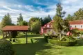 Das Hotel bietet einen gepflegten Garten mit Sitzgelegenheiten und Blick auf das rot gestrichene Hauptgebäude.