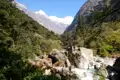 Gebirgsbach und schneebedeckte Gipfel im Himalaya.