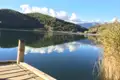 Holzsteg am See mit Blick auf Hügel und Himmel.