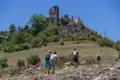 Wandergruppe besteigt den Hügel zu einer verfallenen Burg.