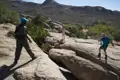 Wanderer beim Überqueren von Felsen in bergigem Gelände mit Hilfe eines Seils.