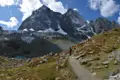 Wanderweg in den Alpen mit schneebedeckten Gipfeln im Hintergrund.