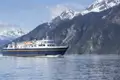 Fähre auf dem Wasser vor schneebedeckten Bergen.