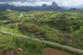Zwei Fahrzeuge auf einer Reise durch eine hügelige Landschaft mit Felsformationen im Hintergrund.