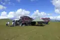 Reisecamp mit Fahrzeugen und Zelt auf einer Wiese.