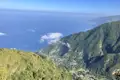 Blick von einem Berghang auf bewaldete Hänge, die zum Meer hin abfallen.