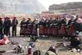 Einheimische in traditioneller Kleidung nehmen an einer Zeremonie vor einer Gebetsfahnenlandschaft teil.