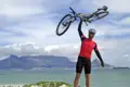 Erfolgreicher Abschluss einer Radtour: Radfahrer mit erhobenem Fahrrad vor dem Tafelberg.
