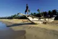 Traditionelles Fischerboot am Strand mit einem Jungen.