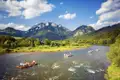 Flöße auf einem Fluss mit Bergen im Hintergrund.