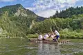 Touristen auf einer traditionellen Floßfahrt auf dem Fluss, umgeben von der natürlichen Schönheit der bewaldeten Hügel.