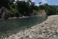 Klares Flusswasser, Kieselstrand und bewaldete Ufer.