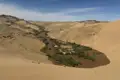 Flusslandschaft inmitten von Sanddünen.