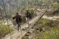 Wanderer überqueren eine Hängebrücke im Gebirge.