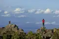 Zwei Personen stehen auf Felsvorsprüngen und betrachten die Landschaft. Einer fotografiert.