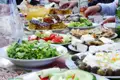 Tisch mit verschiedenen lokalen Spezialitäten, wie Salaten, Käse, Gebäck und Oliven, der im Freien gedeckt ist.