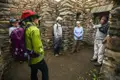 Reisegruppe bei einer Führung durch historische Steingebäude. Ein Führer erklärt Details zur Geschichte und Architektur des Ortes.