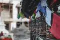 Gebetsmühlen mit tibetischen Mantras und flatternde Gebetsfahnen an einem Tempel.