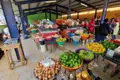 Marktstand mit einer Auswahl an Obst und Gemüse, darunter Zwiebeln, Paprika, Bananen und Orangen.