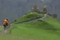Wanderer auf dem Weg zu einer historischen Kirche in den Bergen.