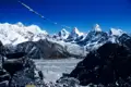 Gebetsfahnen wehen im Wind vor der Kulisse schneebedeckter Himalaya-Gipfel und eines Gletschers.