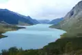 Panoramablick auf einen türkisfarbenen See inmitten einer Berglandschaft.