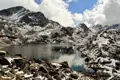 Bergsee mit schneebedeckten Gipfeln im Hintergrund.