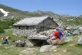 Rast während einer Wanderung: Wanderer pausieren vor einer Berghütte in den Bergen.
