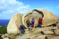 Wanderer ruhen sich an einem großen, ausgehöhlten Felsen während ihrer Wanderung aus.