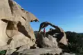 Wanderer auf einem Felsbogen inmitten einer bizarren Felsformation.