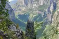 Tiefe Schlucht mit üppiger Vegetation, aufgenommen von einem Aussichtspunkt mit Felsen und Pflanzen im Vordergrund.